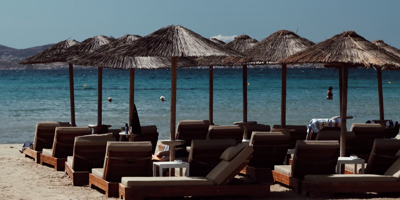 Strand met rieten parasols en ligbedden langs de zee